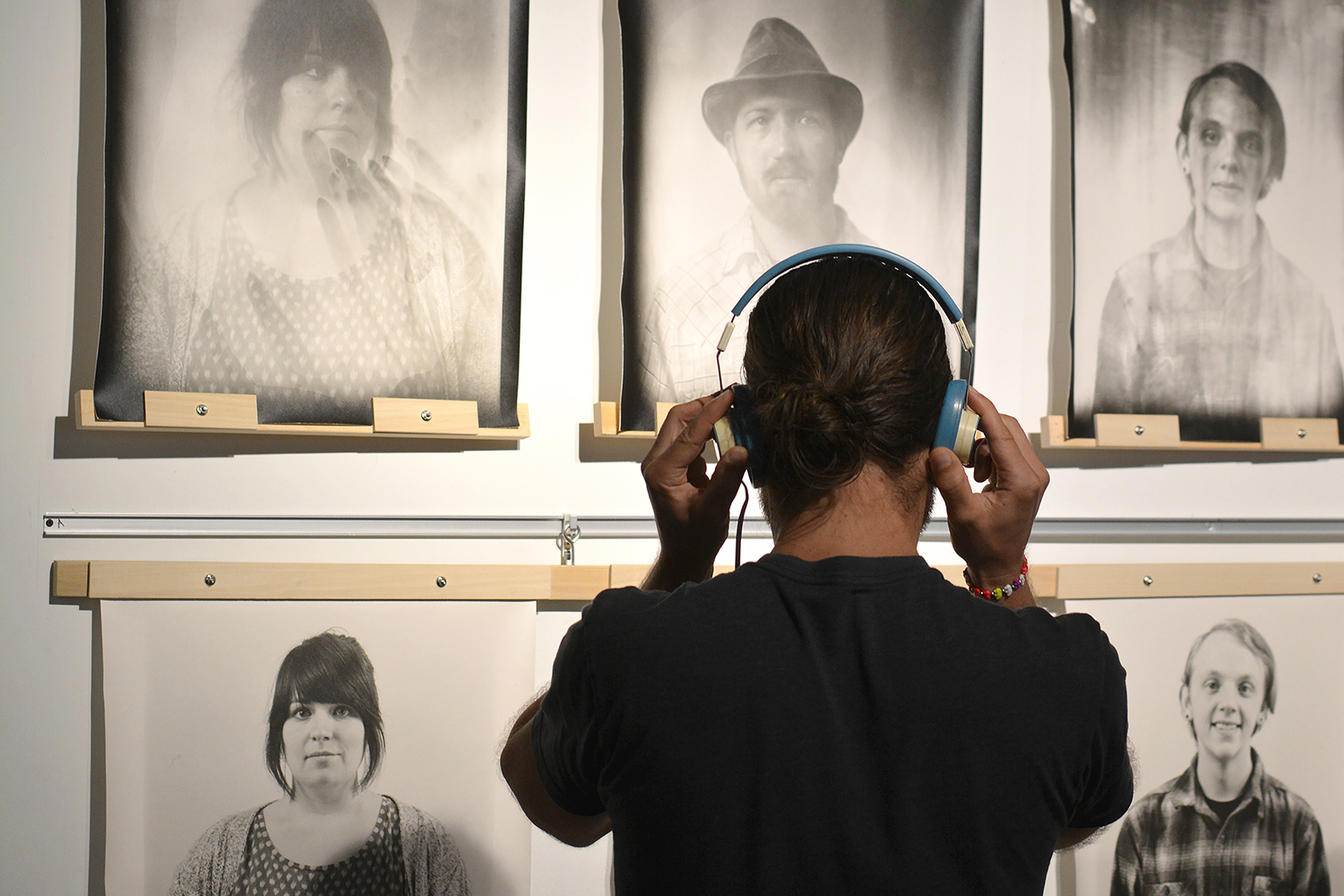 A person spends some time looking at the portraits and listening to a oral history recording.