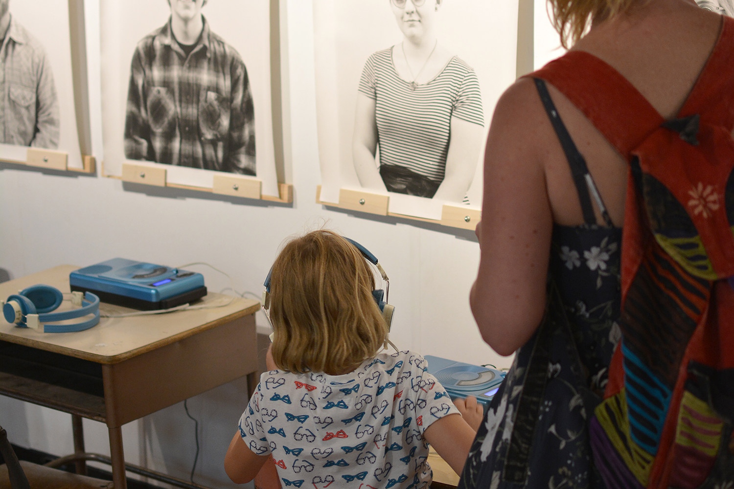 A mother and her kid listening to the oral history recording at a low listening station.